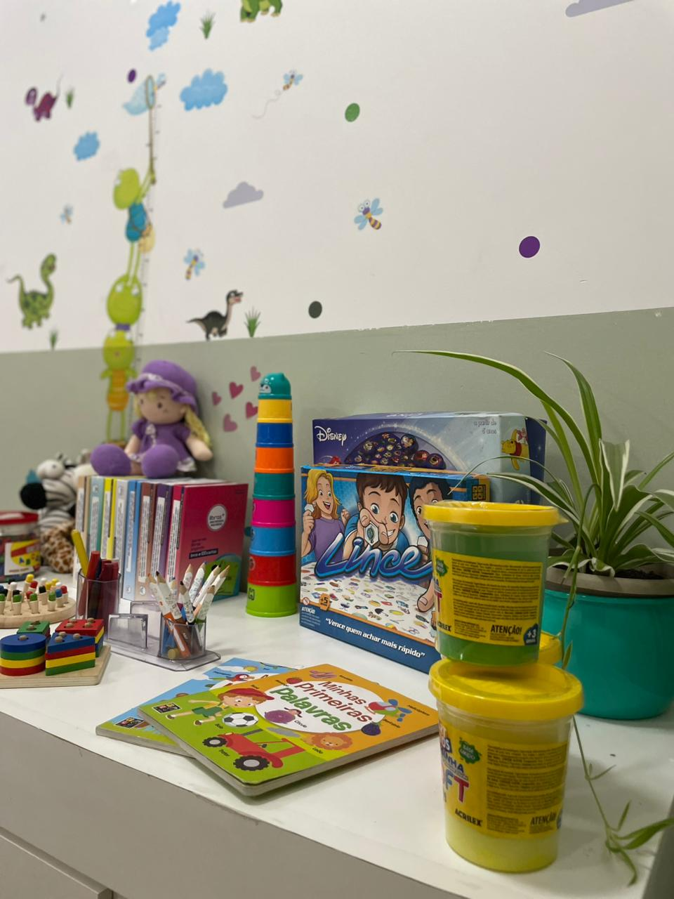 Mesa com brinquedos pedagógicos e livros infantis